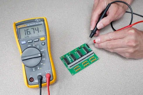 Testing PCB solder joint with multimeter for cold solder joint diagnosis.