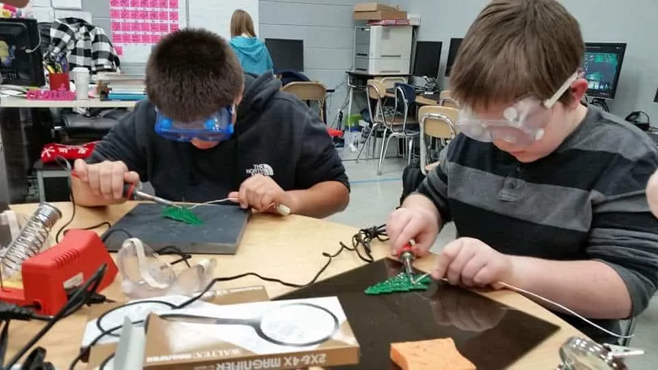 High school student soldering a PCB for a STEM electronics project