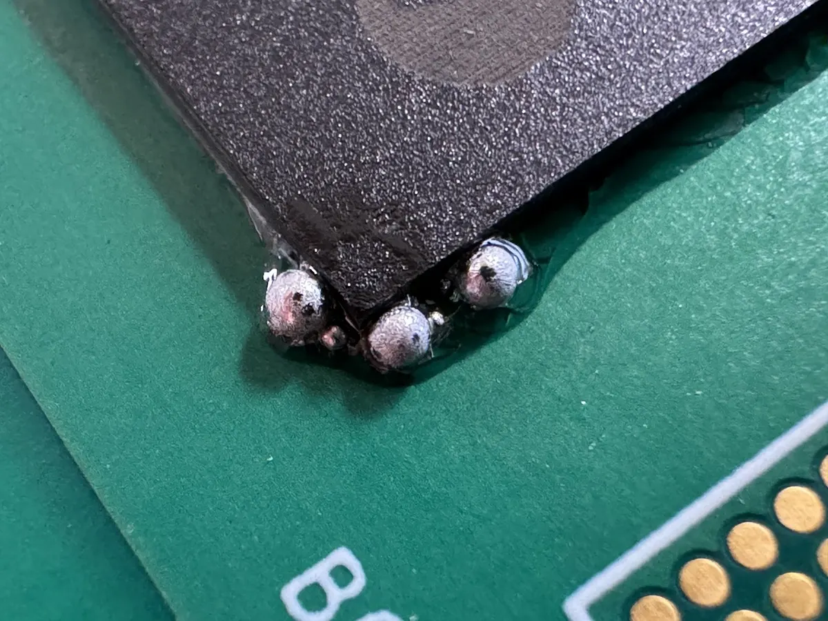 Magnified view of solder ball defects on a PCB.