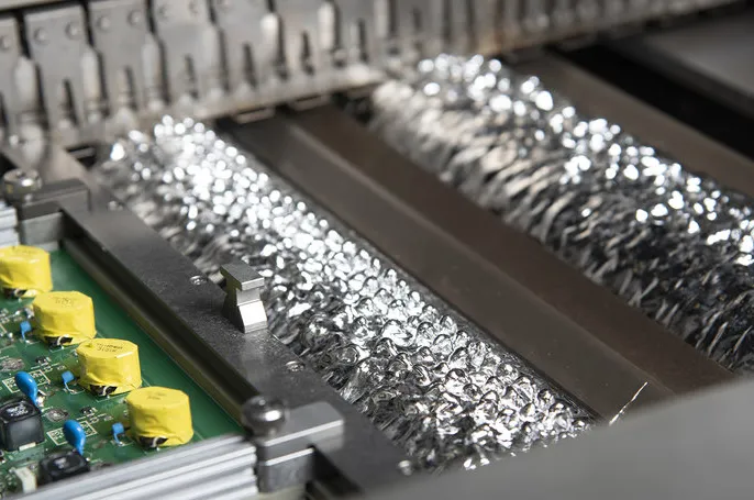 Wave soldering machine in action during PCB assembly.