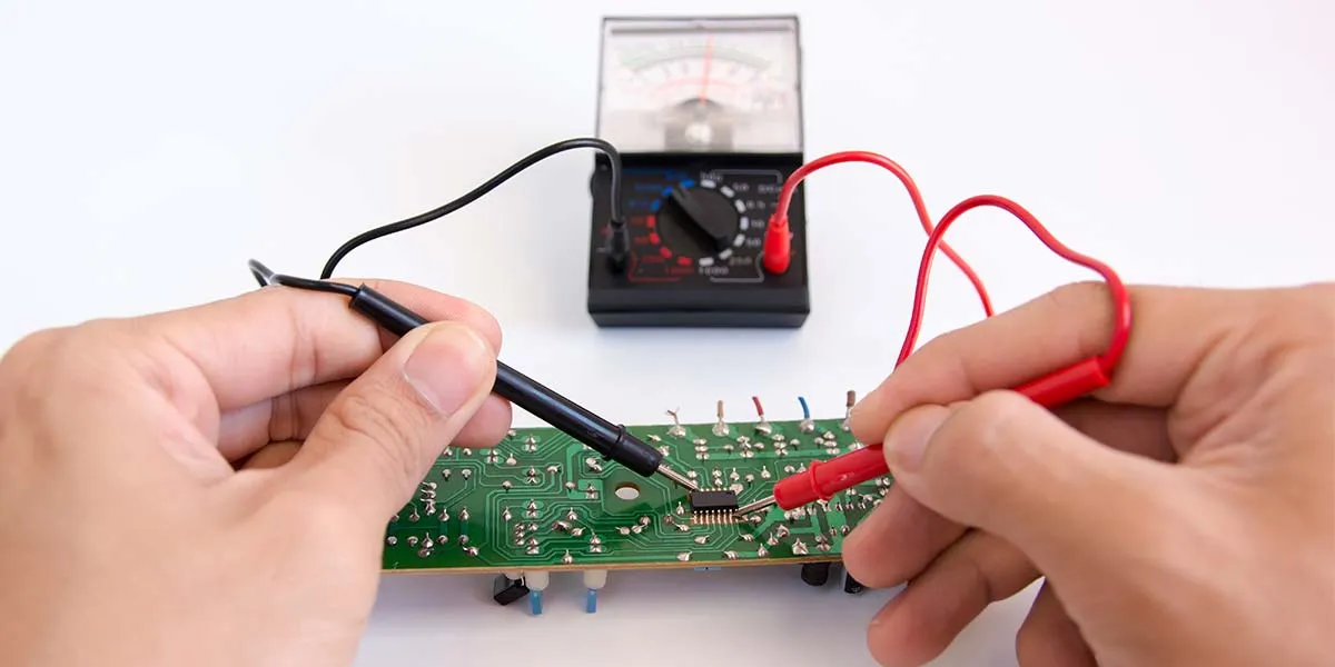 Testing IC pins on PCB with multimeter for troubleshooting