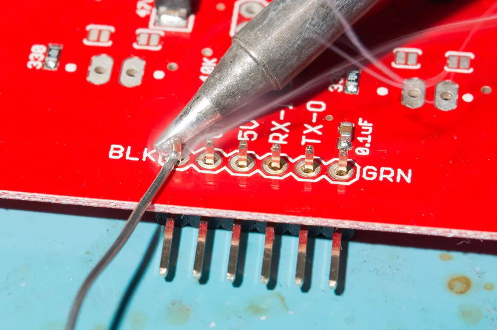 Hand soldering with solder wire on PCB through-hole component.