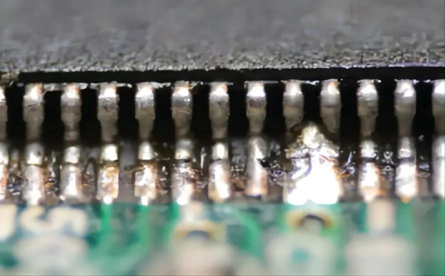 Close-up of a solder bridge defect on a PCB causing a short circuit.