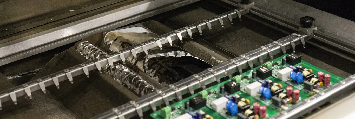 Wave soldering machine connecting through-hole components on PCB.