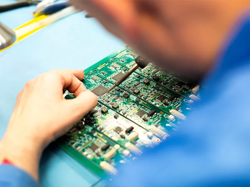 Technician troubleshooting selective soldering defects on a PCB