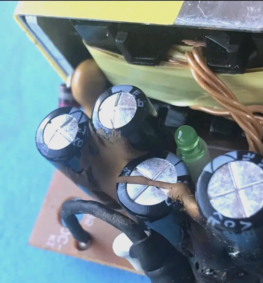Damaged gaming console PCB showing bulging capacitors and cracked solder.