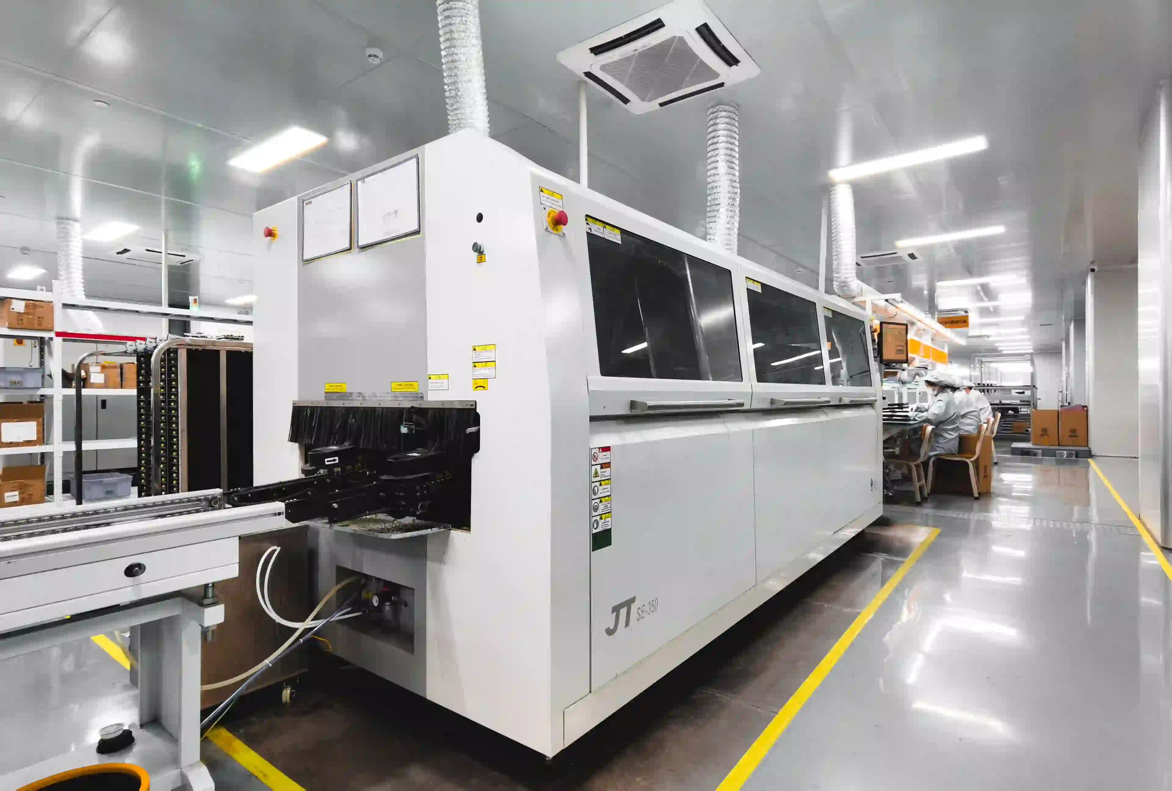Wave soldering machine processing a PCB for through-hole components.
