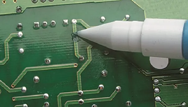 Applying green solder mask repair material to damaged PCB area.