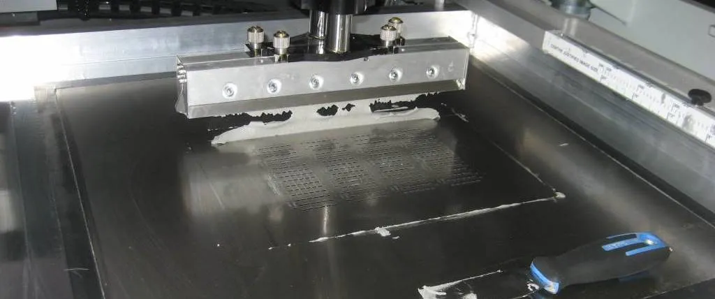 Squeegee blade applying solder paste through stencil apertures on PCB