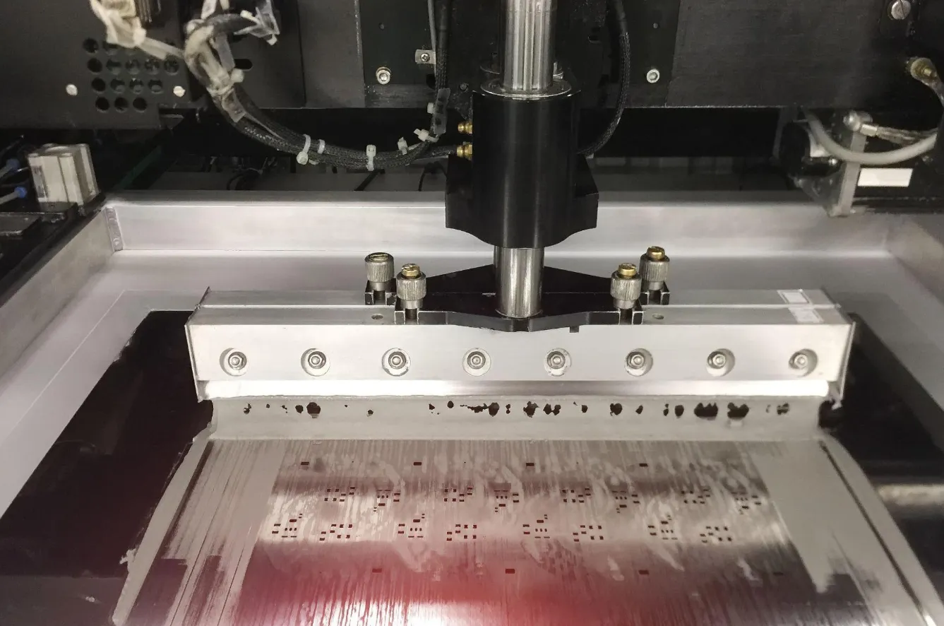 Stencil printer applying solder paste on a PCB for SMT assembly.
