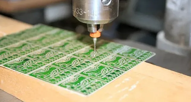 Mechanical drilling machine creating via holes in a multilayer PCB.
