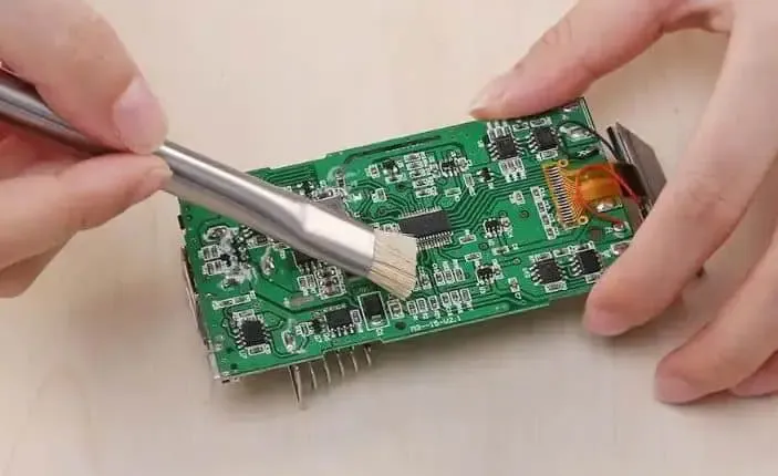 Cleaning flux residue from a PCB using a brush and solvent
