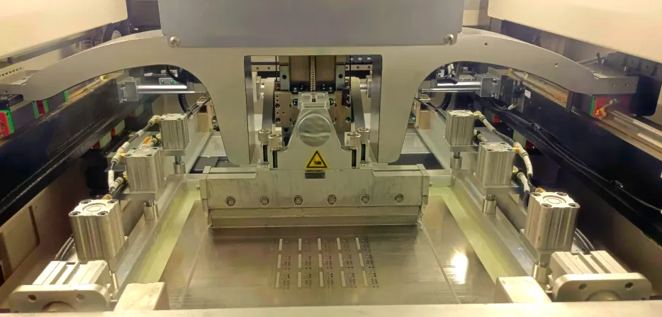 Stencil printing machine applying solder paste on a PCB for SMT assembly.