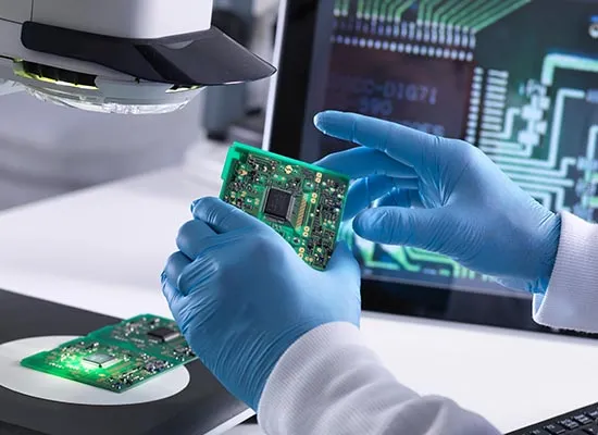 Technician inspecting PCB for plating defects under a microscope