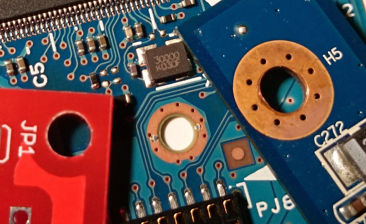 Close-up of a drilled PCB showcasing vias and mounting holes for electrical connectivity.