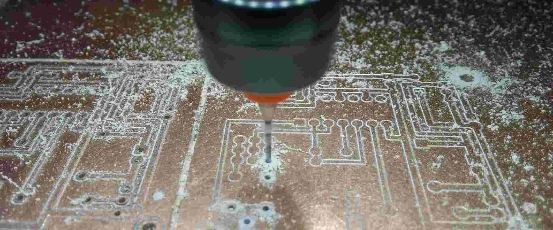 CNC drilling machine creating precise holes on a PCB for electrical engineering projects.