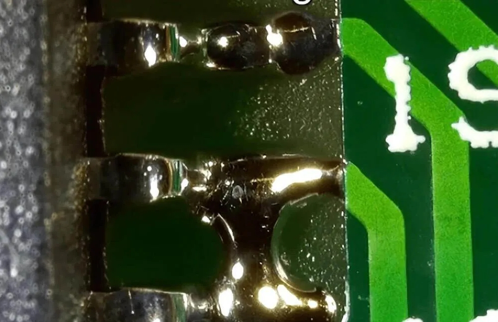 Solder bridging defect on PCB pads after reflow.