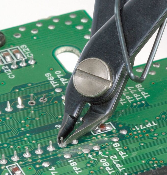 Flush cutters trimming leads on through-hole PCB components."