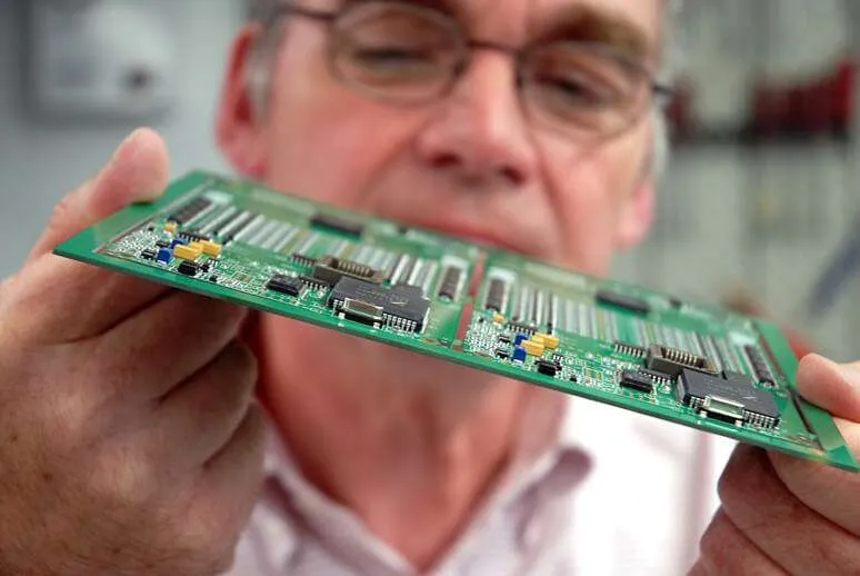 Technician inspecting PCB for pre-treatment quality control.