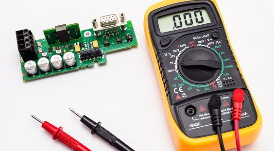 Technician performing fault isolation on MRI PCB with multimeter."