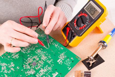 Technician performing continuity testing on an ECU PCB.