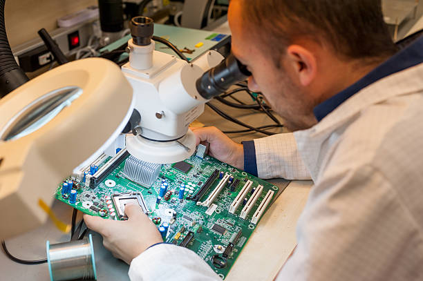 Technician using microscope for manual PCB inspection