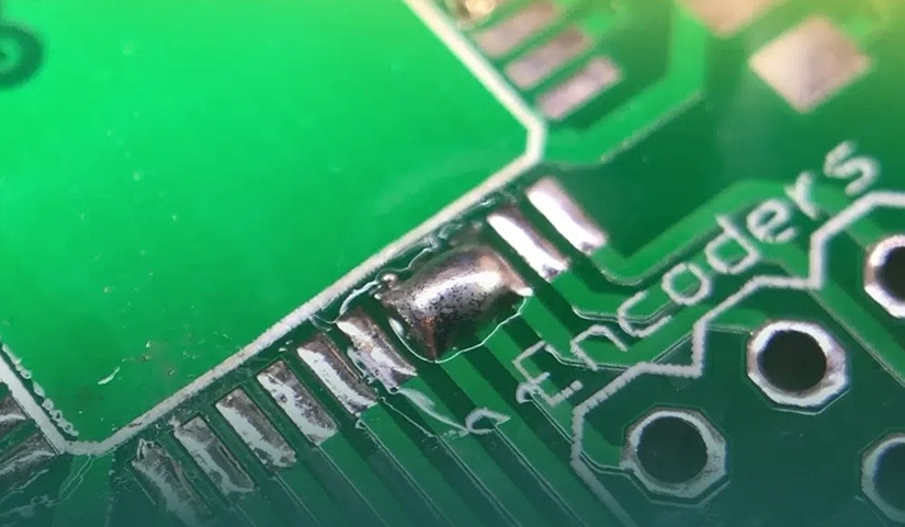 PCB showing a solder bridge defect due to improper solder paste application.