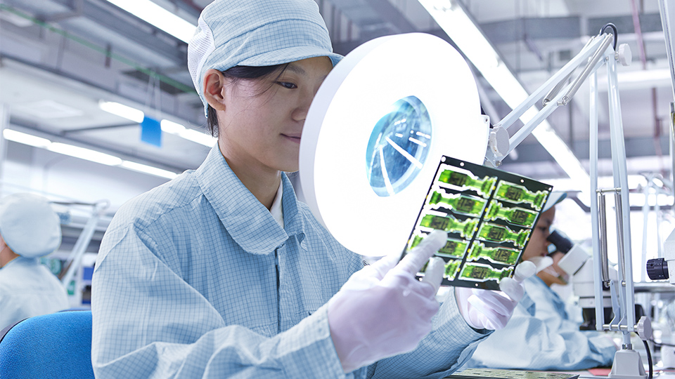 Inspecting a soldered SMD component on an ECU PCB for quality.