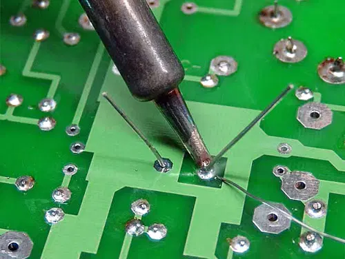 Practicing soldering techniques on a scrap PCB