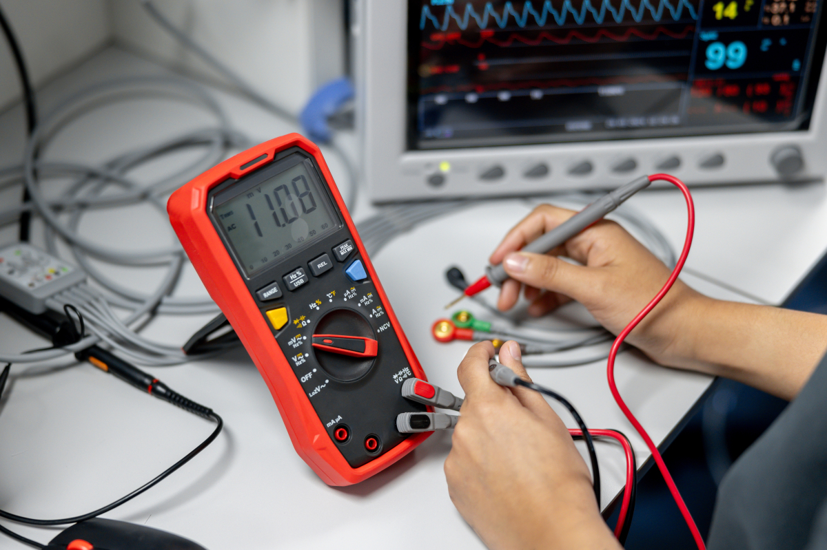 Technician testing a vending machine PCB with a multimeter for fault finding.