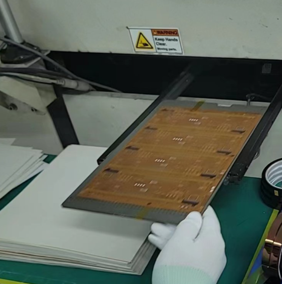 PCB panel in reflow oven with fixtures to prevent warpage.