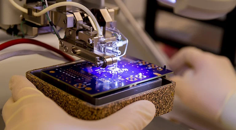 Technician inspecting microelectronics assembly under a microscope