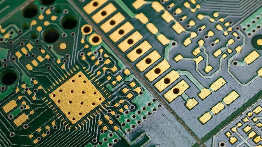 Close-up of PCB with green solder mask and exposed copper pads for SMT components.