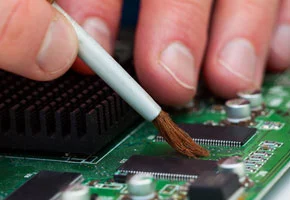 Applying chemical stripper to remove solder mask from PCB.