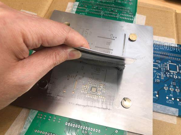Applying solder paste to PCB with stencil for SMT soldering.