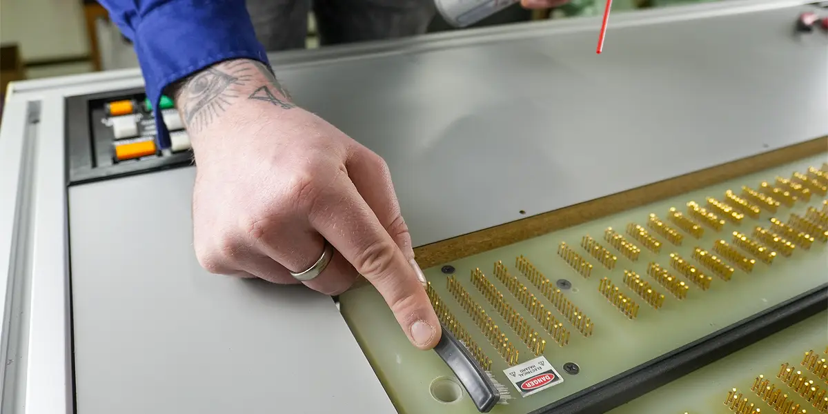 Technician cleaning SMT test probe for maintenance