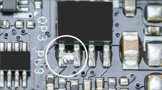 Close-up of a solder bridge defect on a PCB.