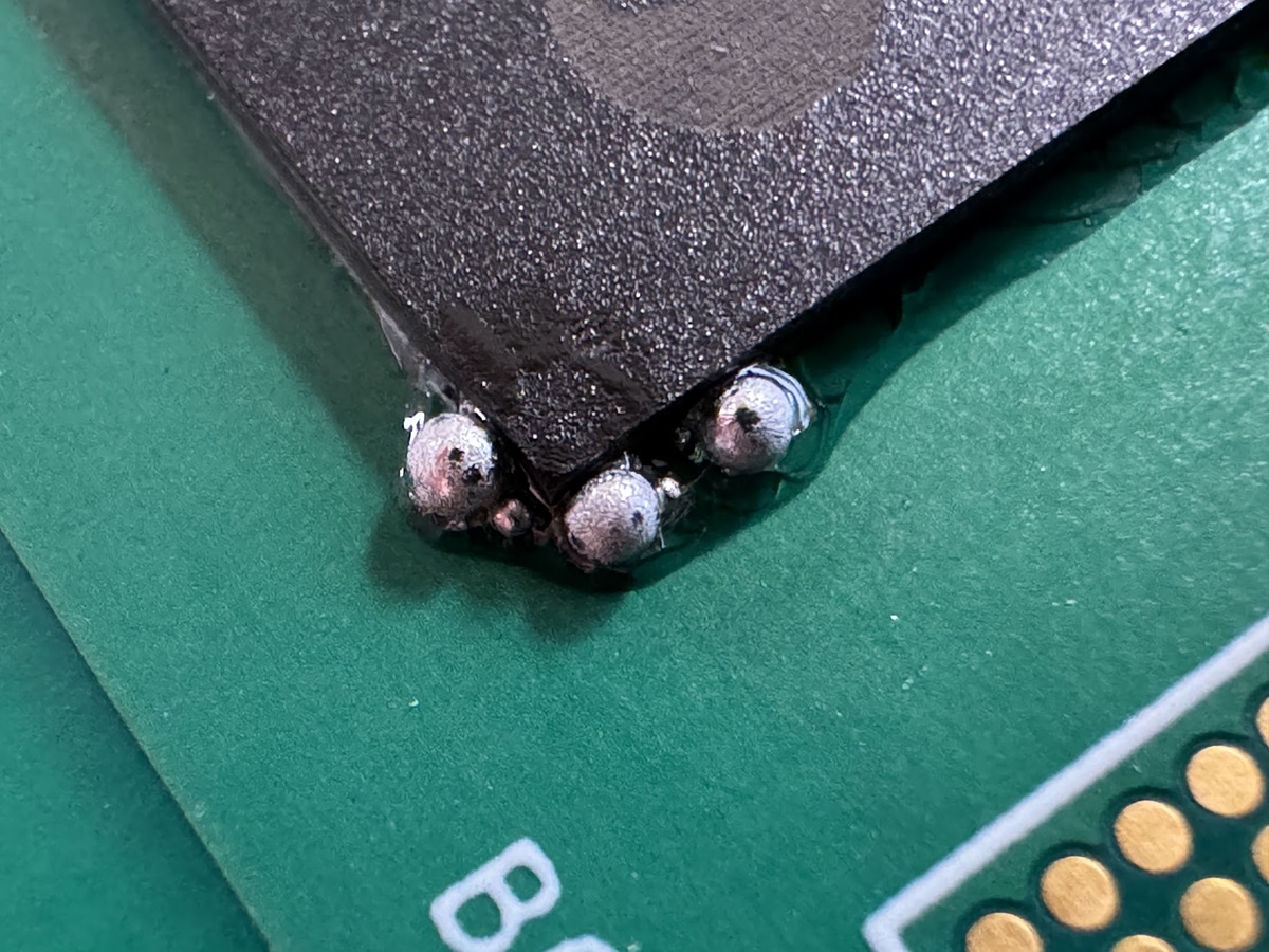 Magnified view of solder ball defects on a PCB.