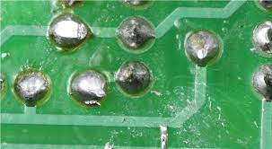 Solder balling defect on SMT PCB assembly with stray solder spheres.