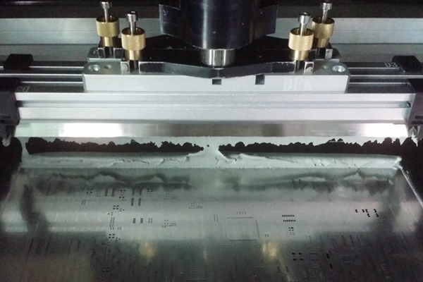 Solder paste application using a stencil for reflow soldering preparation.