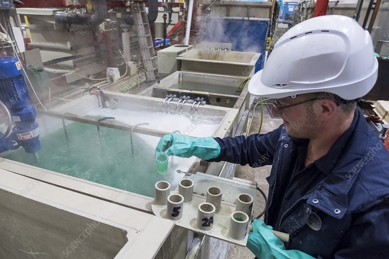 Engineer testing plating bath conditions for hard gold plating quality control.