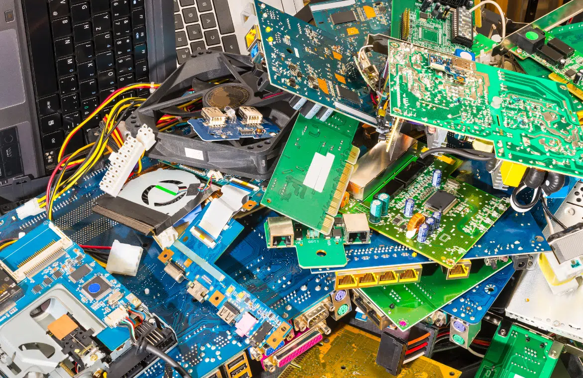 Pile of e-waste in a landfill highlighting the environmental cost of electronics manufacturing.