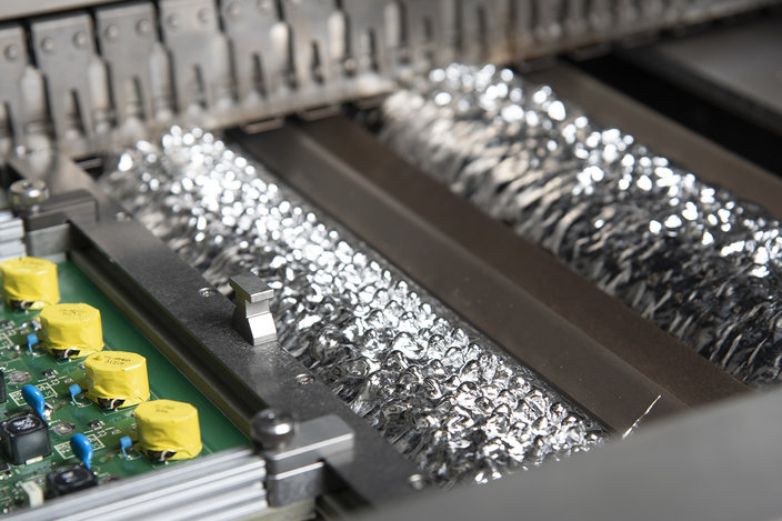 Wave soldering machine using lead-free solder for PCB assembly.