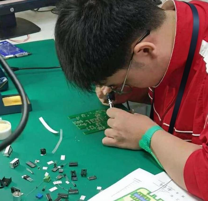 Engineer assembling small batch PCBs on a workbench with manual tools