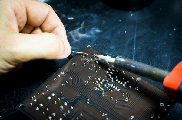 Technician soldering SMD components on high-speed signal generator board