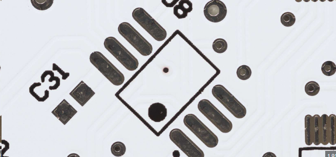 Close-up of black silkscreen text on PCB under bench lighting