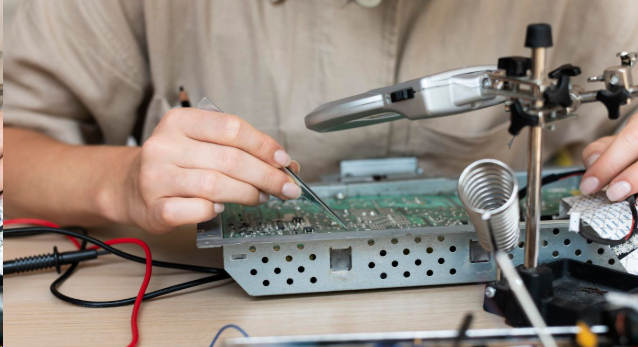 Technician inspecting white silkscreen alignment on PCBs prior to component placement